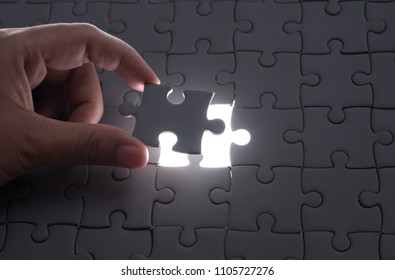 Hand embed missing puzzle piece into place with light glow,success, teamwork and finishing or ending