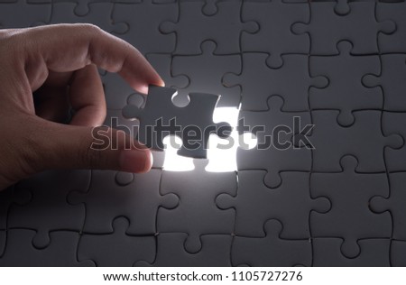 Hand embed missing puzzle piece into place with light glow,success, teamwork and finishing or ending