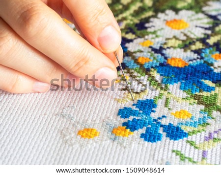 hand embroidering flowers pattern with a needle, hobby concept, close-up