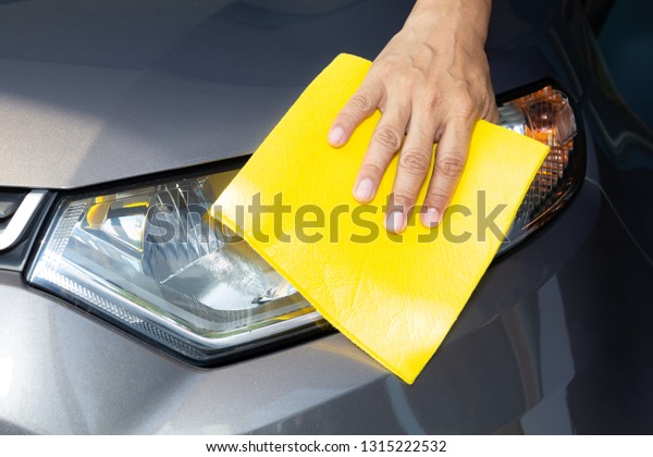 Hand of employees worker\
use clean yellow cloth to wipe the car after washing in the car\
wash shop.