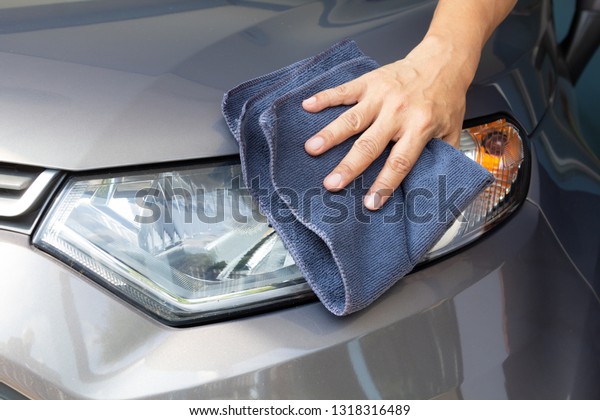 Hand of employees worker\
use clean blue cloth to wipe the car after washing in the car wash\
shop.