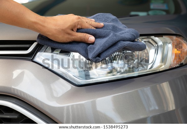 Hand of employees worker use clean blue cloth to\
wipe the car after\
washing.