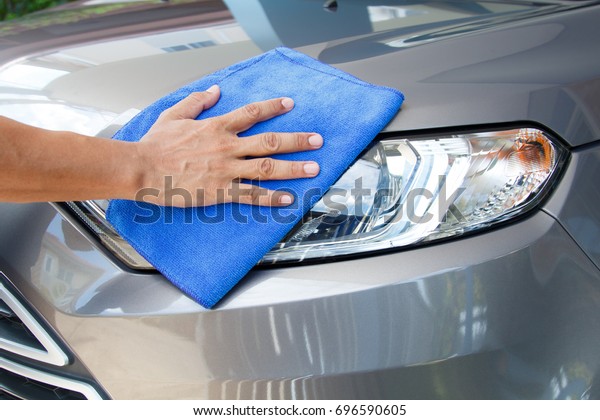 Hand of employees worker use\
clean blue cloth to wipe the car after washing in the car wash\
shop