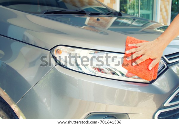 Hand of employees worker use\
clean orange cloth to wipe the car after washing in the car wash\
shop