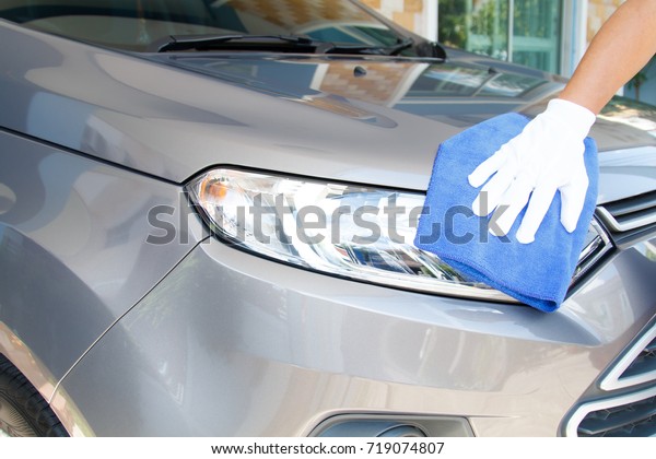Hand of employees\
worker use clean blue cloth with glove to wipe the car after\
washing in the car wash\
shop