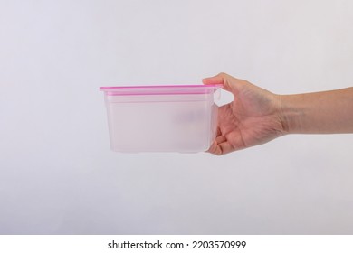 Hand And Empty Plastic Lunchbox On A White Background.