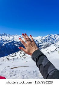 A Hand With The Engagement Ring And Mountain Chain As Backdrop. Lots Of Snow Everywhere. Beautiful Weather In Heiligenblut, Austria. Apres Ski Relaxation.