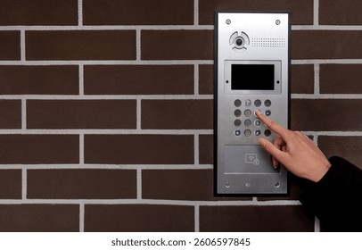 Hand entering code on keypad at building entrance. Space for text.