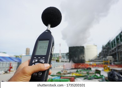 Hand of Environmental officer holding to use sound level meter for monitor is part of the prevention of environmental impacts at Chemical plant area or refinery factory.