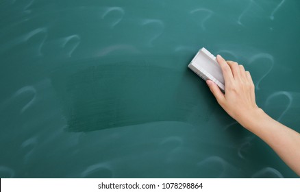 Hand erasing question mark on chalkboard