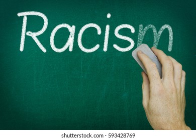 Hand Erasing The Word RACISM Written On Blackboard