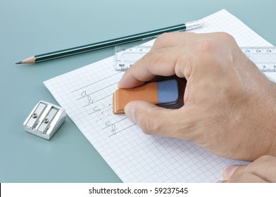 Hand erasing a writed mistake on a white paper during a writing exercise