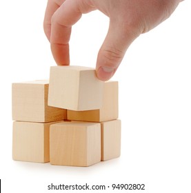 The hand establishes a wooden cube. It is isolated on a white background