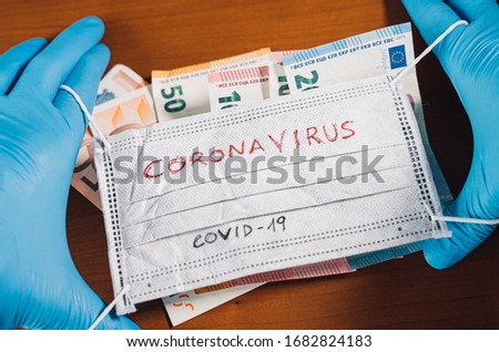 Hand with euro bills covering a face mask with the word coronavirus. Global stock markets, financial crisis or medical profit caused by the coronavirus outbreak Foto stock © 