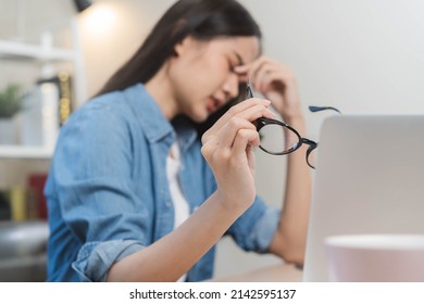 Hand of exhausted, stressed asian young business woman working, took off glasses, massage nose from dry eyes, suffer on hard work while use laptop computer at office home. Overtime job, debt problem. - Shutterstock ID 2142595137
