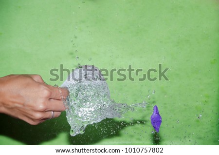 
Hand exploding a water balloon with a needle
