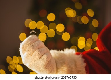 Hand Of Father Christmas Holding Engagement Ring At Home In The Living Room