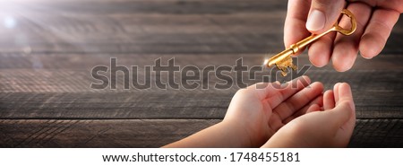 Hand Of Father Giving Old Golden Key To Child - Inheritance Concept