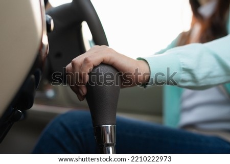 Hand female driver using automatic gear shift system in car. Woman shifting an automatic car.