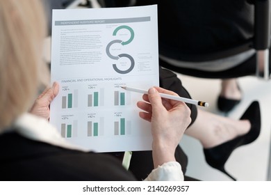 Hand of female economist with pencil pointing at chart in financial document while preparing report about company income - Shutterstock ID 2140269357