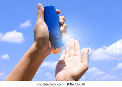 Hand Of Female Holding Sunscreen. Very Sun Light Sky Background.Health Concepts And Skin Care