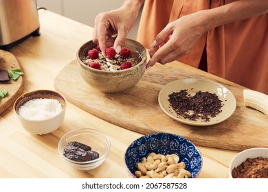 Mano de hembra poniendo frescas frescas frescas maduras sobre limo o postre casero en tazón mientras decora la comida
