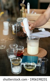 Hand Of Female Putting Transparent Liquid Substance Into Glassware With Melted Soap Mass While Making Mixture For Handmade Cosmetics