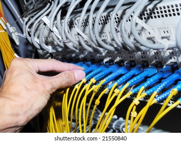 Hand With Fiber Cables Connected To Servers In A Datacenter