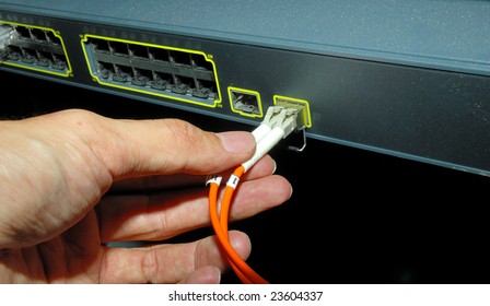 Hand With Fiber Cables Connected To Servers In A Datacenter