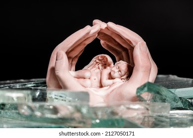 Hand Figurine Protect An Angel On Broken Glass. Child Protection Concept. High Quality Photo