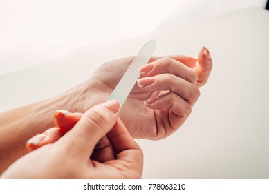 Hand Filing Nails With Glass Nail File On The White Background