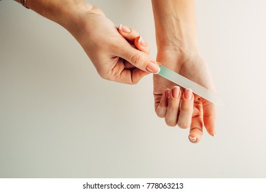Hand Filing Nails With Glass Nail File On The White Background