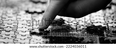Hand with finger completing a jigsaw puzzle for fun and achievement