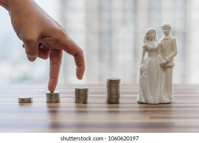 Hand With Fingers A Man Putting On Coin, Bride And Groom Model And Looking For Saving Money For Getting Married, Collect Money For Getting Married. Business Ideas Concept With Blurred Background.