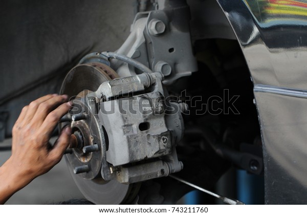 Hand fixing car\'s\
brake system in a garage