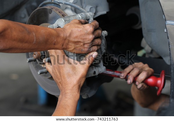 Hand fixing car\'s\
brake system in a garage