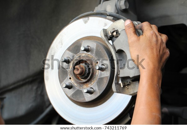 Hand fixing car's
brake system in a garage
