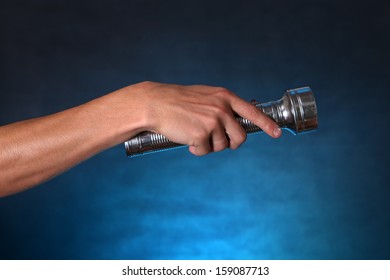 Hand With Flashlight On The Dark Background