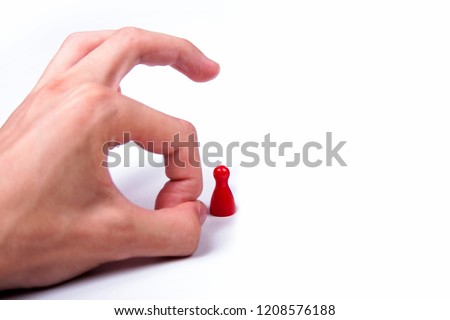 Hand flicking a single red game piece on white background, elimination