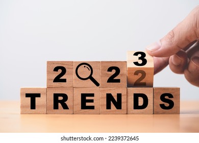 Hand flipping 2022 to 2023 trend year for marketing monitor and business planing change concept.