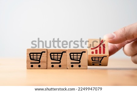 Hand flipping change between increasing graph and shopping cart trolley which print screen on wooden block cube for commerce business sales and order growth concept.