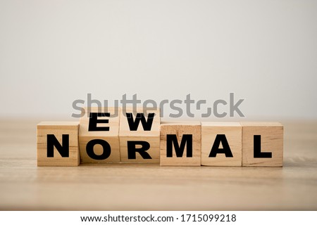 Hand flipping wooden block cubes for new normal wording. The world is changing to balance it into new normal include business , economy , environment and health.