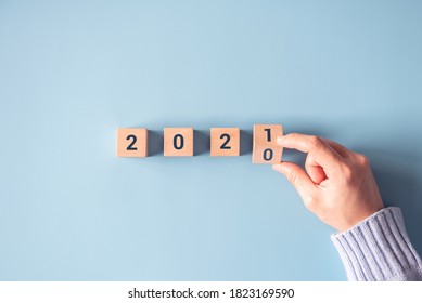 Hand flipping wooden blocks for change year 2020 to 2021 on blue paper background. New year and holiday concept.
