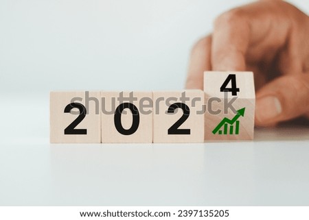 Hand flipping wooden cube block inscribed 2024 and growth icon on smart background, Positive indicators banner. Business growth concept in 2024. Business goals and achievement. Sustainable development