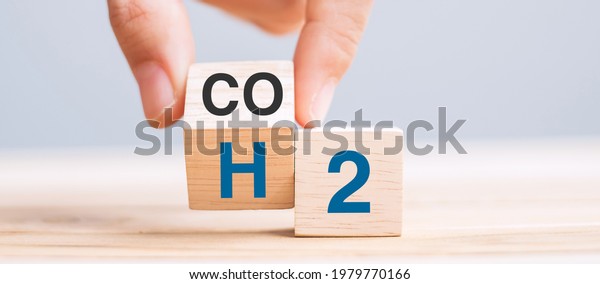 hand flipping\
wooden cube blocks with CO2 (Carbon dioxide), change to H2\
(Hydrogen) text on table background. Free Carbon, alternative\
energy and global climate change\
concepts