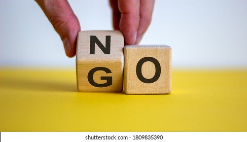 Hand flips a cube and changes the word 'no' to 'go'. Beautiful yellow table, white background. Concept. Copy space. - Shutterstock ID 1809835390