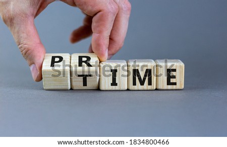 Hand flips a cube and changes the word 'prime' to 'time' or vice versa. Beautiful grey background. Business concept. Copy space.