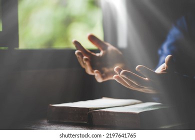 Hand folded in prayer to god on Holy Bible book in church concept for faith, spirituality and religion, woman person praying on holy bible in morning. christian catholic woman hand with Bible worship. - Shutterstock ID 2197641765