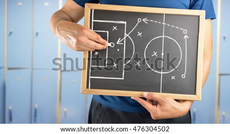 hand of a football coach drawing a tactics of soccer game  with white chalk on blackboard at changing room