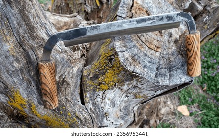 A hand forged drawknife sits on a tree stump waiting to be put to good use shaving and shaping wood by a skilled artisan. Bokeh. - Powered by Shutterstock